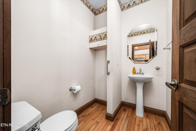 bathroom with wood-type flooring, a sink, toilet, and baseboards