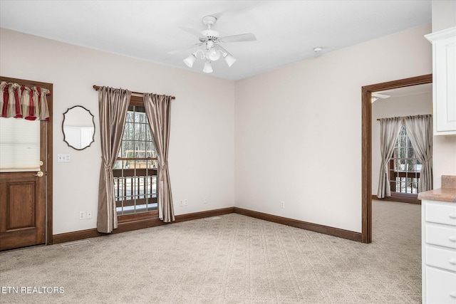 spare room featuring ceiling fan, baseboards, a wealth of natural light, and light colored carpet