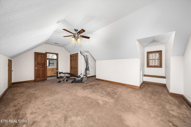 workout area with baseboards, a ceiling fan, lofted ceiling, carpet, and a textured ceiling