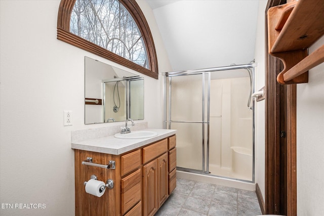 full bathroom featuring vaulted ceiling, a stall shower, and vanity