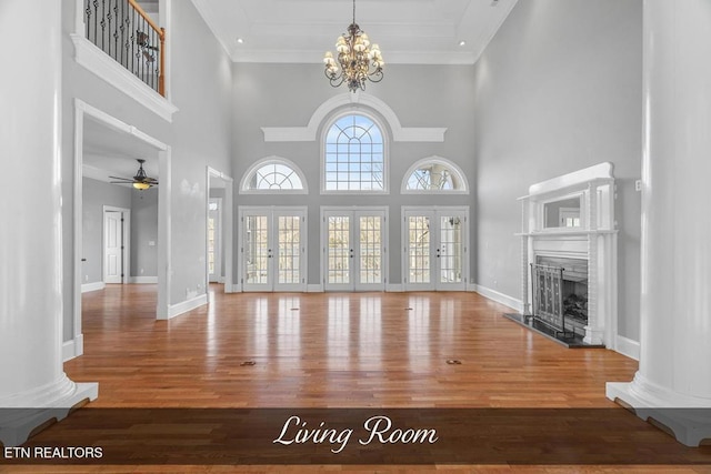 unfurnished living room with a fireplace with raised hearth, french doors, wood finished floors, and baseboards