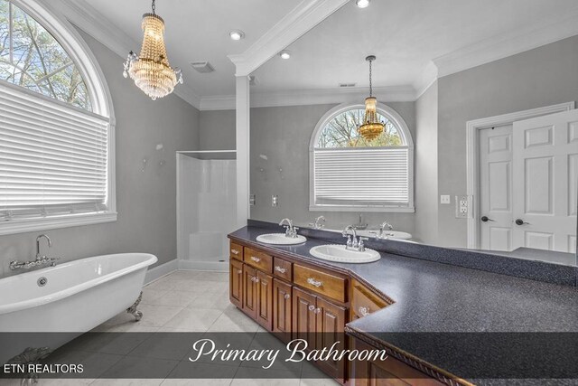 full bath featuring ornamental molding, a freestanding tub, tile patterned flooring, and a sink