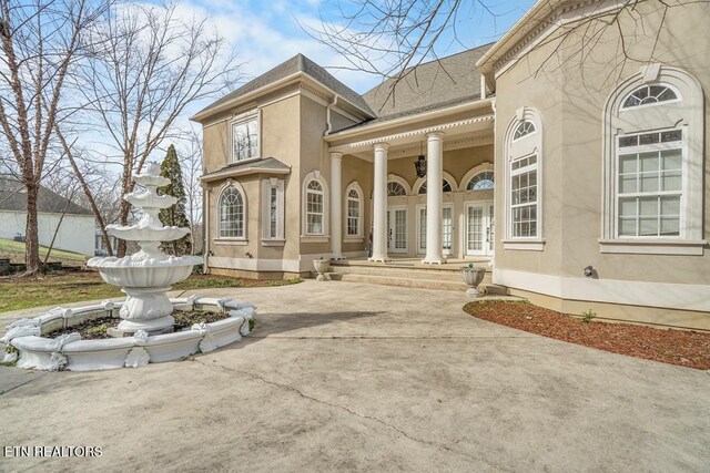 doorway to property with a shingled roof and stucco siding