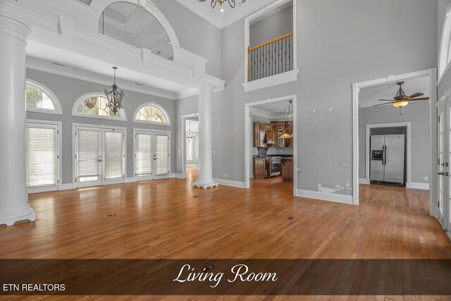 entrance foyer featuring ornate columns, baseboards, crown molding, and wood finished floors