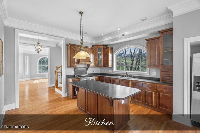 kitchen featuring dark countertops, a sink, glass insert cabinets, and a center island