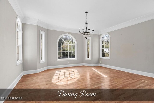 unfurnished dining area featuring baseboards, a healthy amount of sunlight, a notable chandelier, and light wood finished floors