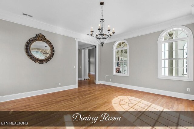 spare room featuring visible vents, crown molding, and wood finished floors