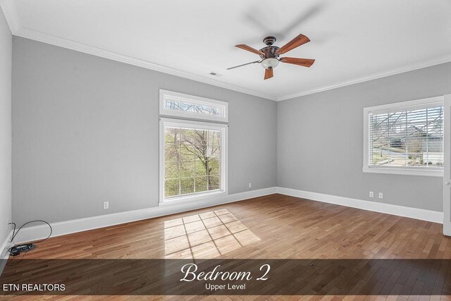 empty room with baseboards, wood finished floors, and crown molding