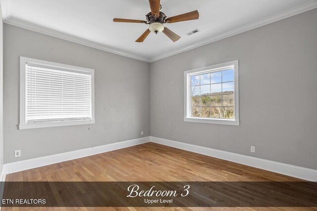 unfurnished room with baseboards, crown molding, visible vents, and wood finished floors