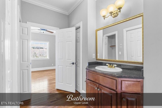 bathroom with crown molding, ceiling fan, vanity, wood finished floors, and baseboards