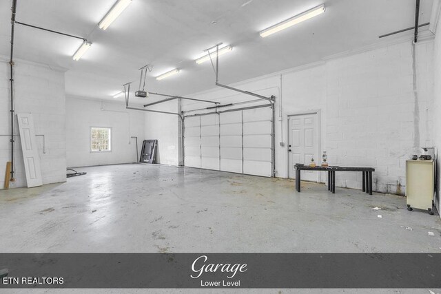 garage featuring concrete block wall and a garage door opener