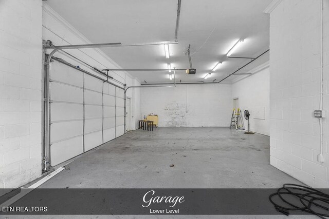 garage featuring concrete block wall and a garage door opener