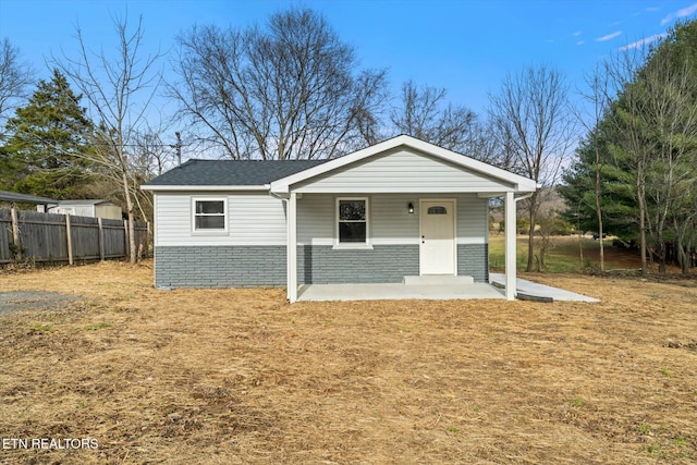 view of front of home featuring brick siding, a front yard, and fence