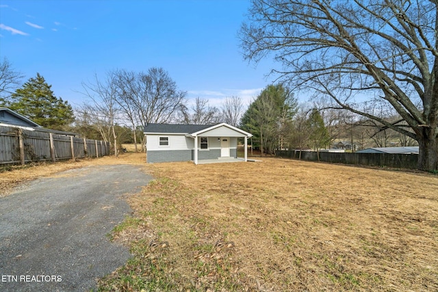 view of front of property with aphalt driveway, a front yard, and fence