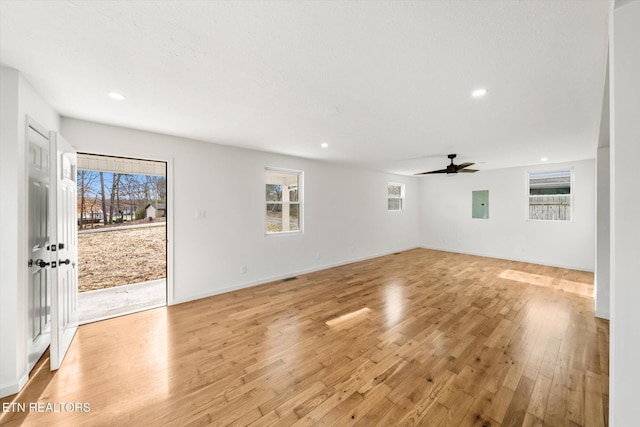 unfurnished living room with light wood finished floors, electric panel, baseboards, and recessed lighting