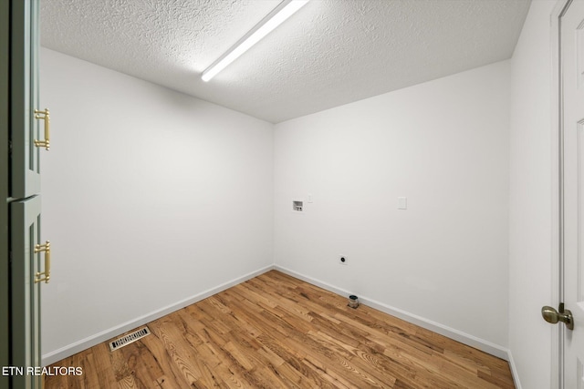 unfurnished room with baseboards, a textured ceiling, visible vents, and wood finished floors