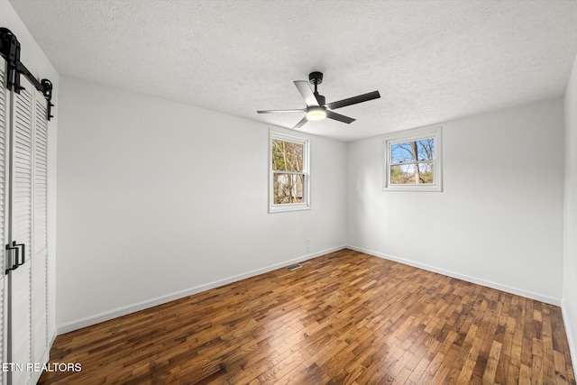 unfurnished bedroom featuring a barn door, baseboards, and wood finished floors