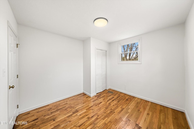 unfurnished bedroom featuring a closet, baseboards, and wood finished floors