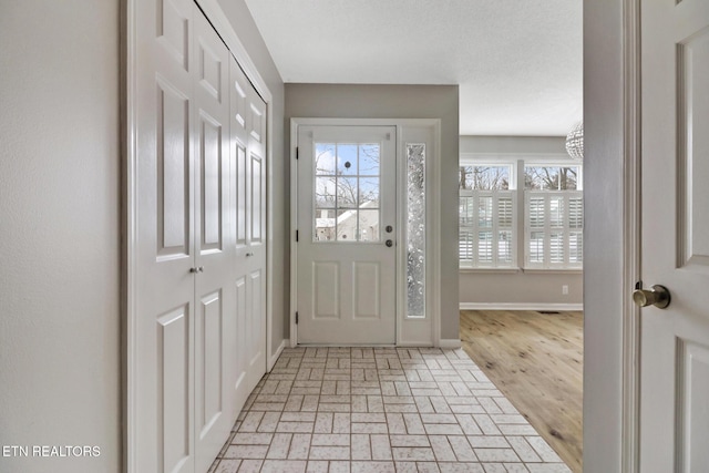 foyer entrance featuring brick floor and baseboards