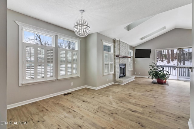 unfurnished living room with lofted ceiling, a fireplace, visible vents, baseboards, and light wood-style floors