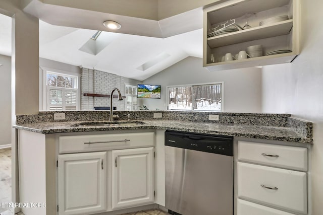 kitchen with a sink, white cabinets, dishwasher, open shelves, and dark stone countertops