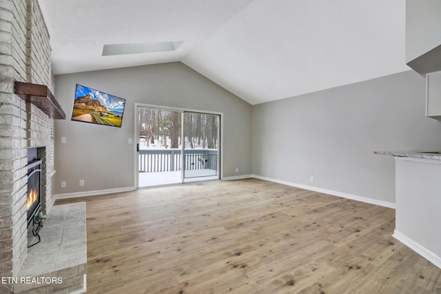 unfurnished living room with light wood-type flooring, a fireplace, lofted ceiling, and baseboards