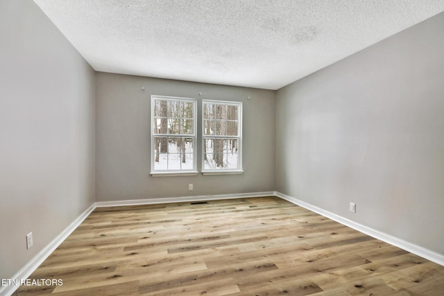 unfurnished room featuring baseboards, a textured ceiling, and light wood-style floors