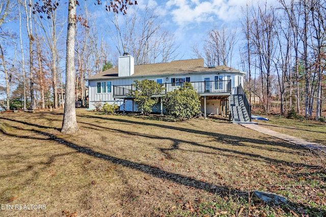 rear view of house with stairway, a yard, board and batten siding, a wooden deck, and a chimney