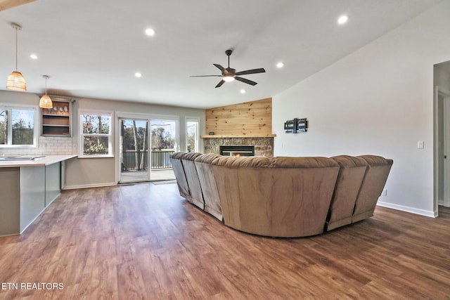unfurnished living room featuring a stone fireplace, recessed lighting, baseboards, and dark wood-style flooring