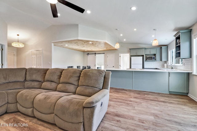 living room with light wood finished floors, recessed lighting, ceiling fan, and vaulted ceiling