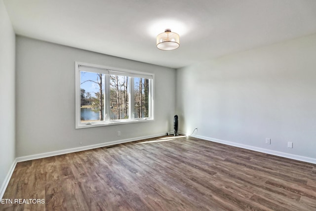 spare room featuring baseboards and dark wood-style flooring