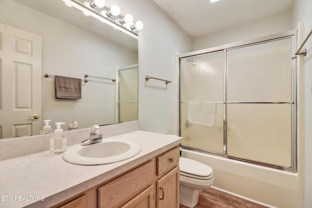 full bathroom with vanity, toilet, wood finished floors, and combined bath / shower with glass door