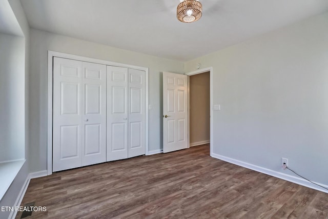 unfurnished bedroom featuring a closet, baseboards, and wood finished floors