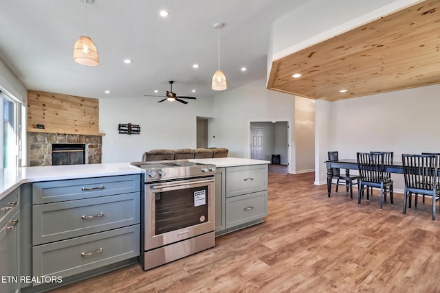 kitchen featuring light countertops, open floor plan, gray cabinets, and stainless steel range