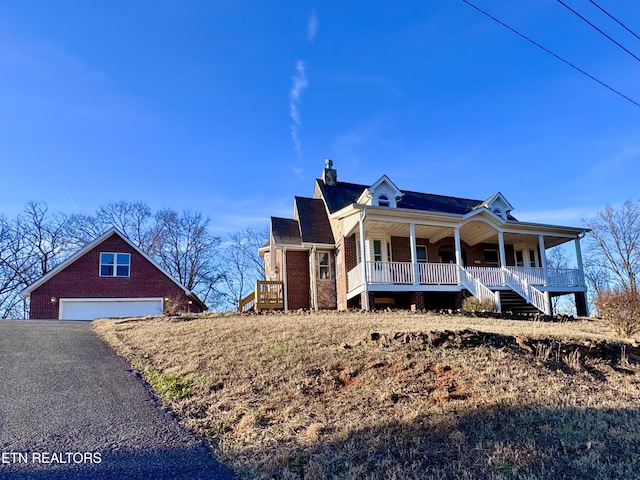 view of front of home featuring covered porch, a garage, and an outbuilding