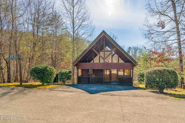 view of front of house featuring log exterior, aphalt driveway, and a detached carport