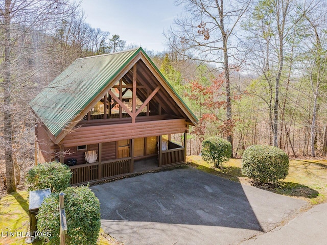 view of front facade featuring metal roof, driveway, and log siding