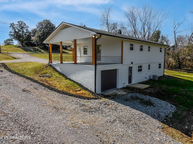 view of side of property featuring covered porch, driveway, an attached garage, and central AC unit