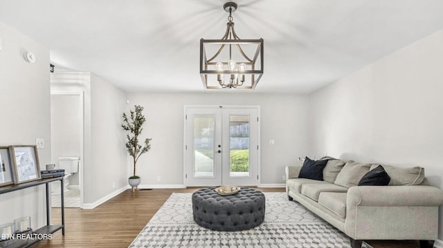 living room with a chandelier, french doors, and hardwood / wood-style floors