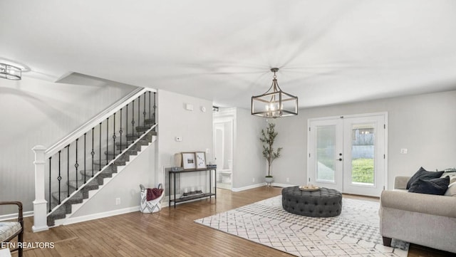 living room with a notable chandelier, french doors, and wood-type flooring