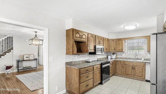 kitchen with an inviting chandelier, sink, backsplash, decorative light fixtures, and stainless steel appliances