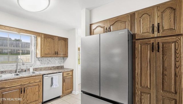 kitchen with appliances with stainless steel finishes, sink, light tile patterned floors, and tasteful backsplash