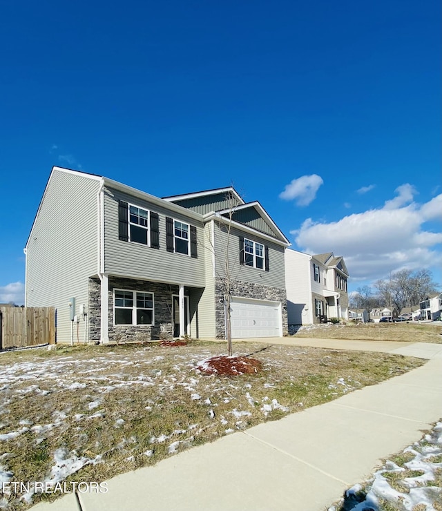 view of front facade with a garage, stone siding, and fence