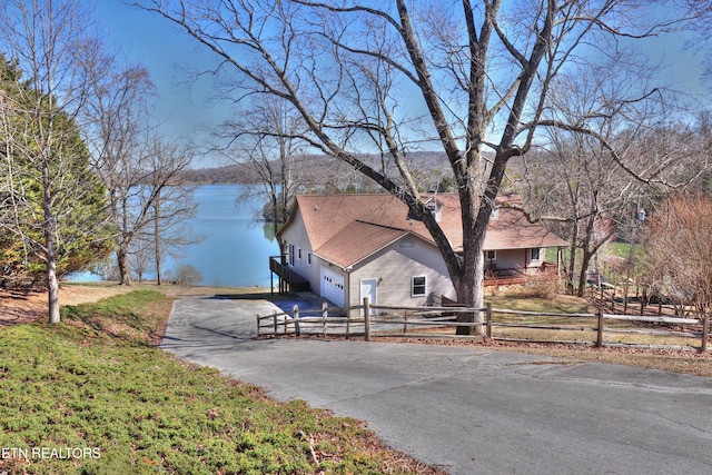 exterior space featuring a fenced front yard, a water view, driveway, and a garage