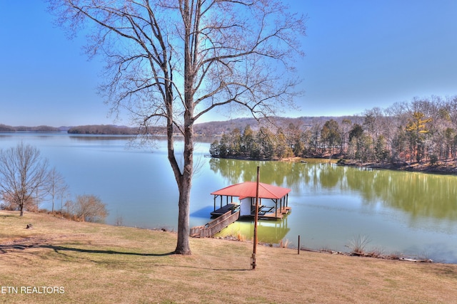 view of dock with a water view, a lawn, and boat lift