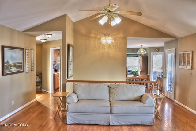 living room featuring a ceiling fan, baseboards, vaulted ceiling, and hardwood / wood-style floors