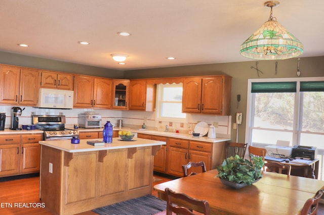 kitchen with brown cabinets, white microwave, stainless steel electric range, and light countertops