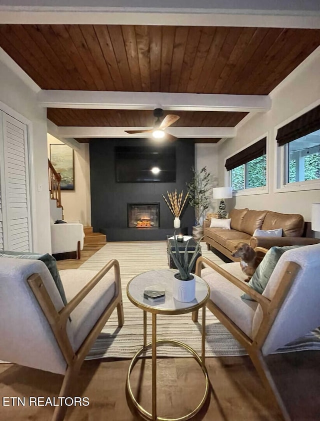 living room featuring ceiling fan, beam ceiling, a fireplace, and wooden ceiling