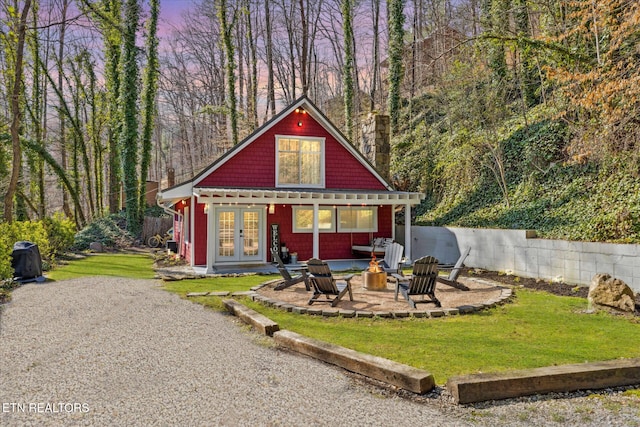 exterior space featuring a fire pit, a front yard, french doors, and a patio