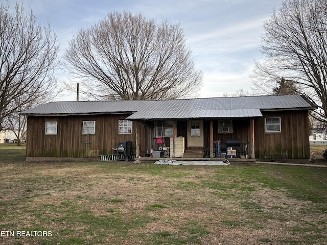 rear view of house featuring metal roof and a yard